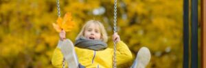 A little girl wearing yellow swings on a swing set