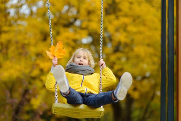 A little girl wearing yellow swings on a swing set