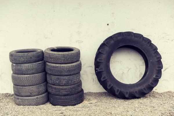 Two stacks of old car tires and one large truck tire